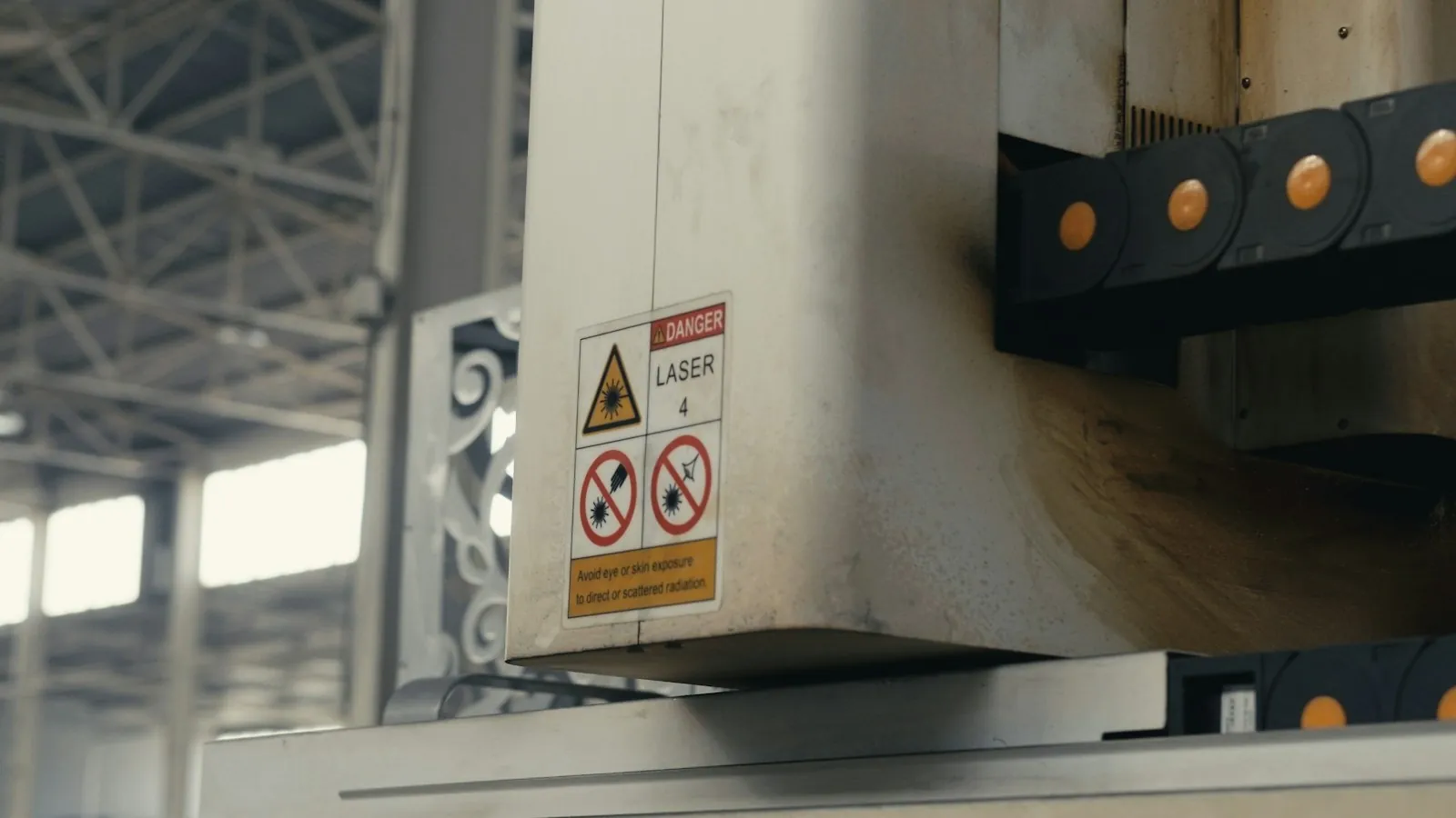 Close view of industrial laser equipment with a visible laser hazard label