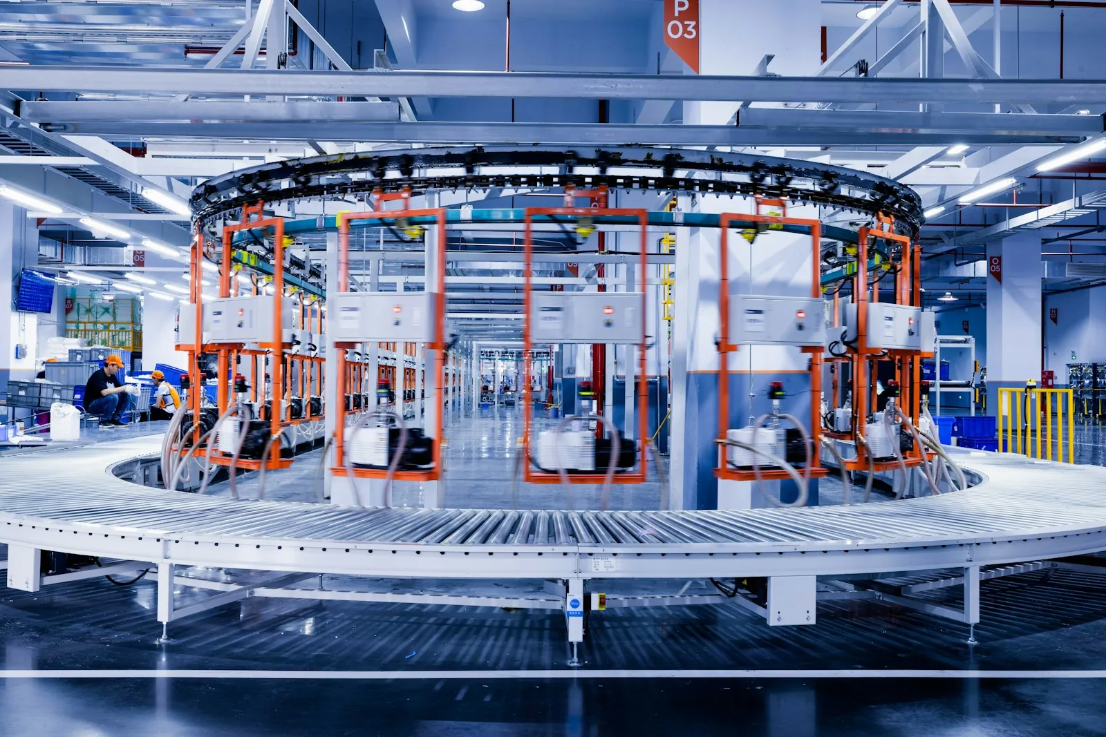 Automated manufacturing line with orange equipment frames and metal workstations