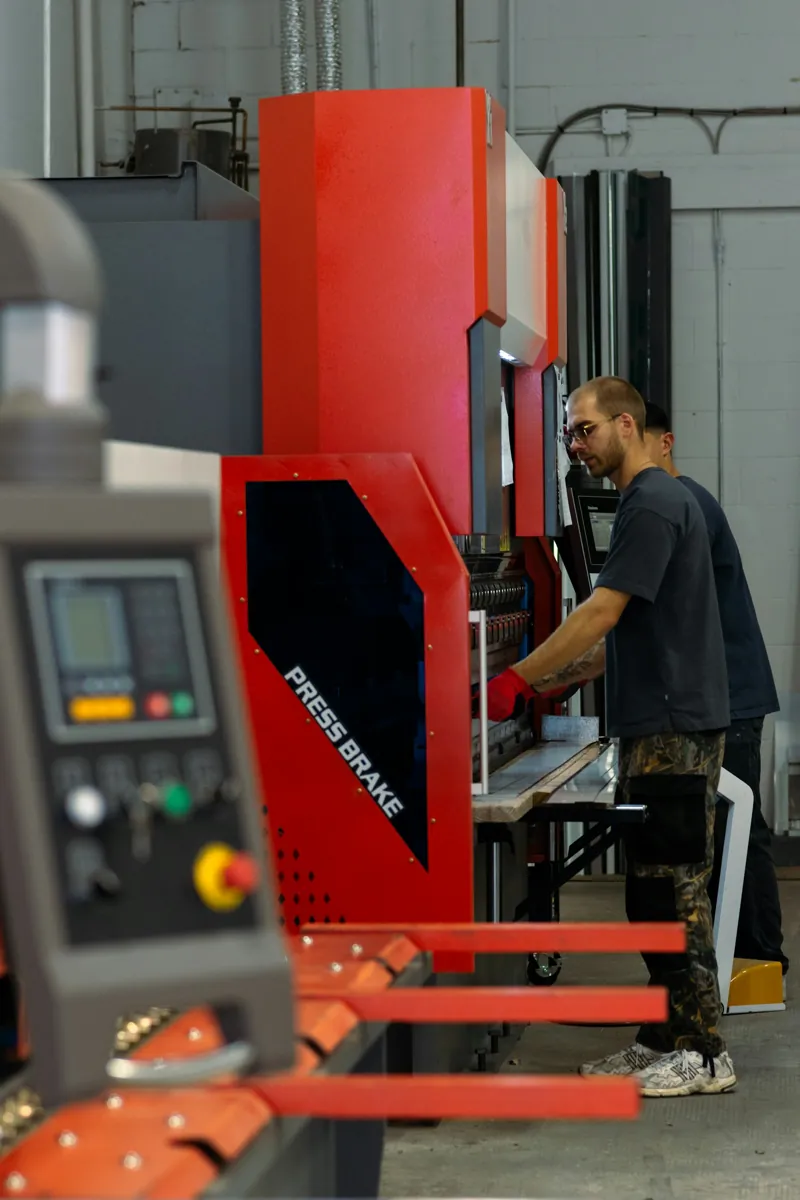 An operator working beside a metalworking machine in a workshop